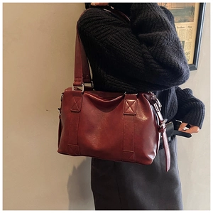 Close-up of a burgundy leather tote bag with decorative stitching and metal zipper