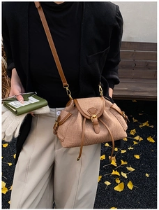 Detail of vintage drawstring bucket bag with leather trim and pleated texture in autumn setting