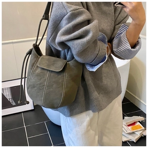 Olive green bucket bag with contrast stitching and drawstring closure shown on model