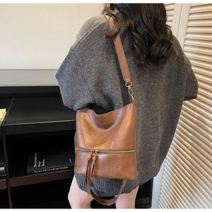 Détail du sac hobo marron vintage avec fermeture éclair en métal et double pompons