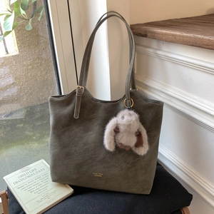 Detail of vintage olive green tote bag with plush rabbit charm and gold buckle