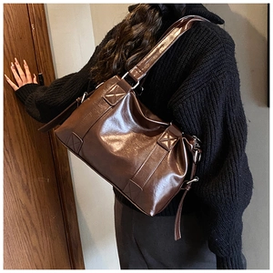 Brown vintage PU leather tote bag with X-shaped stitching shown on a shoulder