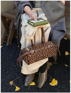 Detail of leopard print boston bag with leather handles and silver hardware accents