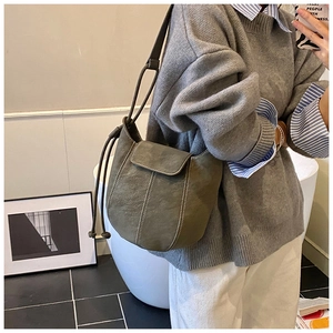 Detailed side view of olive green matte suede bucket bag with contrast stitching on model