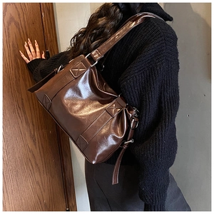 Detail showing high-gloss oil-wax leather texture and reinforced cross-stitching on a brown tote
