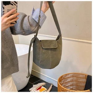 Detail of sage green bucket bag showing contrast stitching and smooth leather texture
