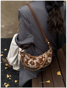 Detail view of animal print crescent bag with leather strap and chain in autumn setting
