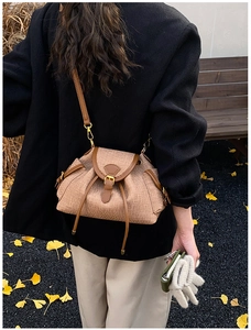 Outdoor back view of woven fabric and brown leather bucket bag on a model