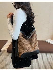 Detail of leopard print bucket bag with gold studs and black leather strap worn by a model