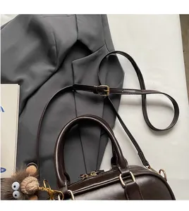Detail der dunkelbraunen Retro-Bowlingtasche mit verstellbarem Gurt und Plüsch-Anhänger
