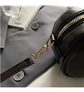 Detailaufnahme von goldfarbenem Reißverschluss und Karabiner an schwarzer Tasche
