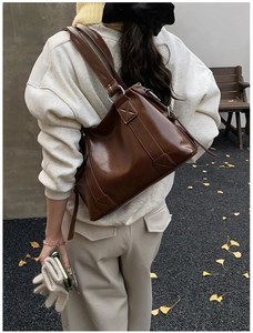Detailed back view of a brown oily leather tote bag with silver rings on wide straps