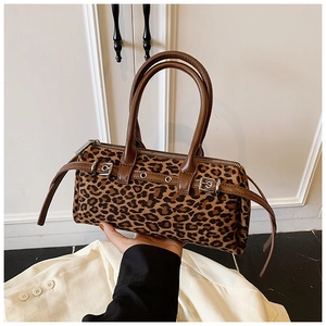 Detail of leopard print plush handbag with brown leather straps and silver buckles