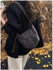 Detail of grey frosted suede bucket bag with white contrast stitching on black blazer
