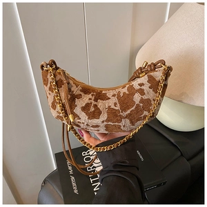 Detail of cow-print half-moon bag with golden chain and thin leather shoulder strap
