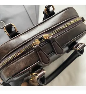 Details der glatten goldenen Reißverschlüsse an einer braunen Vintage-Handtasche