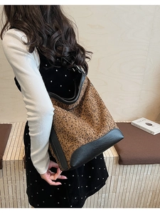 Detail of leopard print bucket bag with black leather panels and shoulder strap
