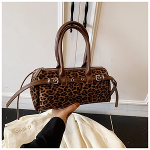 Detail view of leopard print plush barrel bag featuring brown leather handles and buckle strap