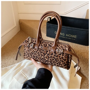 Detail view of leopard print barrel bag showing faux fur texture and leather handles