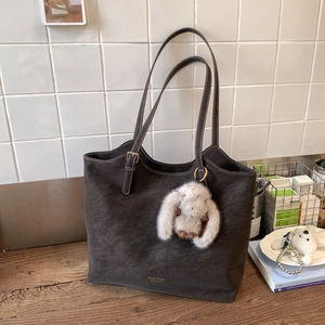 Detail view of deep brown large tote bag with plush rabbit charm and gold buckle accents