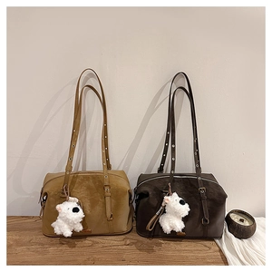 Detail of retro khaki and dark brown suede shoulder bags with plush dog charms on wood