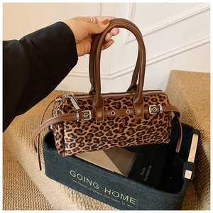 Detail of leopard print cylindrical handbag with leather handles and metallic buckle hardware