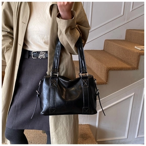 Detail view of black semi-matte leather tote bag with stylish cross-stitch handle accents