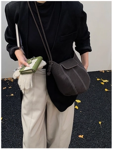 Detail of dark brown bucket bag with contrast stitching on a model in autumn setting