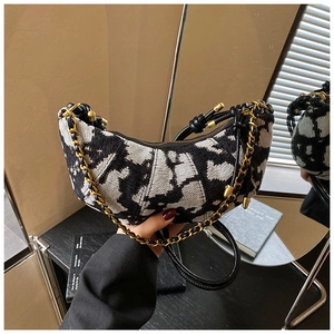 Detail of black and white abstract textured crescent bag with gold chain and leather strap