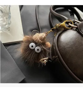 Detailansicht eines Plüsch-Monsters mit Strickmütze an einer braunen Tasche
