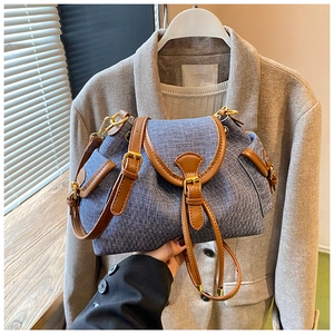 Close-up of vintage blue and white tweed bucket bag with leather trim and gold hardware
