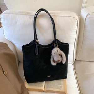 Detail of black tote bag with white contrast stitching and grey plush rabbit charm
