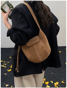 Brown frosted leather bucket bag with white contrast stitching on a model in autumn street