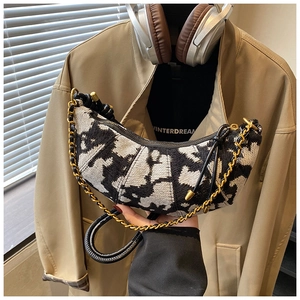 Detail of half-moon bag featuring black and white jacquard pattern and gold chain link