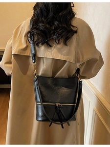 Sac seau classique en similicuir noir avec pompon et fermeture éclair sur un mannequin