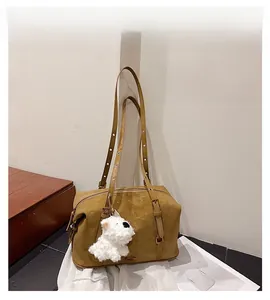 Detail view of vintage camel suede boston bag with silver studs and cute plush dog charm