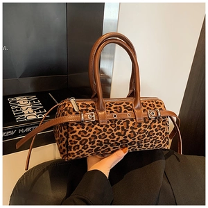 Close-up of leopard print barrel bag with brown leather handles and silver hardware detail