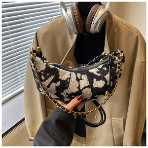 Close-up of crescent underarm bag with black and white jacquard pattern and gold chain