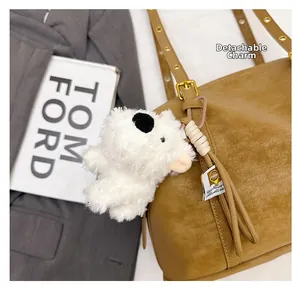 Detailed view of plush white dog charm on brown leather handbag with cotton rope