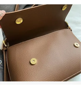 Close-up of brown litchi grain leather bag with premium gold magnetic metal buckle