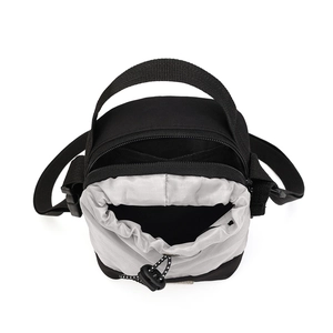 Detail van functionele outdoor schoudertas met dubbel compartiment en trekkoordsluiting