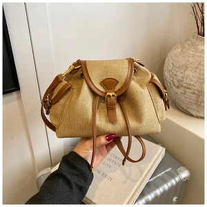 Detail of retro drawstring bucket bag with straw texture, brown leather trim and gold buckle