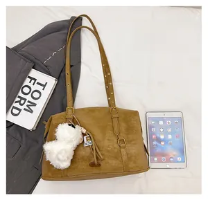 Detail view of vintage brown tote bag with leather texture and white plush pendant