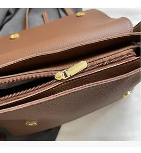 Detail of brown litchi leather bag showing golden zipper and magnetic closure