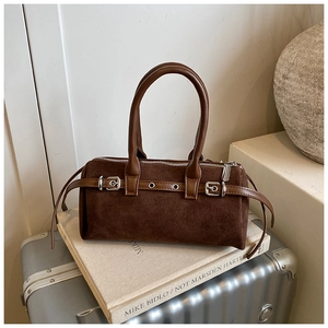 Close-up of vintage brown suede Boston bag with leather handles on a retro background