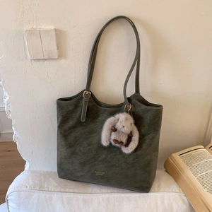 Detail of vintage olive green leather tote with gold logo and plush rabbit charm
