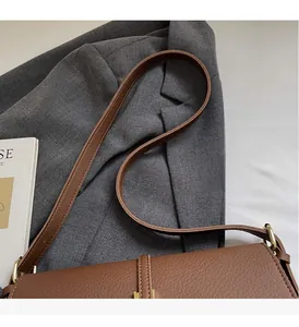 Close-up of brown litchi grain leather shoulder bag with sturdy stitching and metal buckle