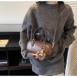 Retro dark brown crossbody bag with plush monster charm worn over a gray knit dress