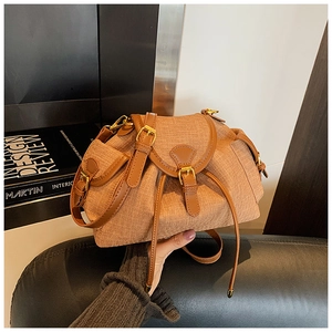 Detail of brown woven crossbody bag featuring leather trim and functional side pockets