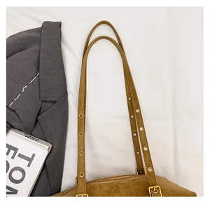 Macro detail of adjustable shoulder strap and gold eyelets on a brown suede pillow bag